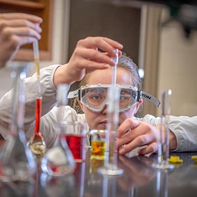 SURVE student dropping chemicals into a beaker.